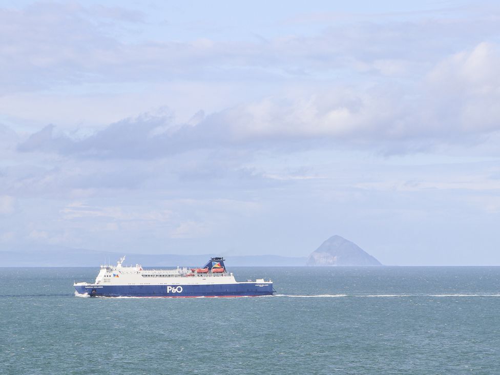 A ferry sailing on the ocean with an island in the background at Squirrel Cottage Kirkcolm