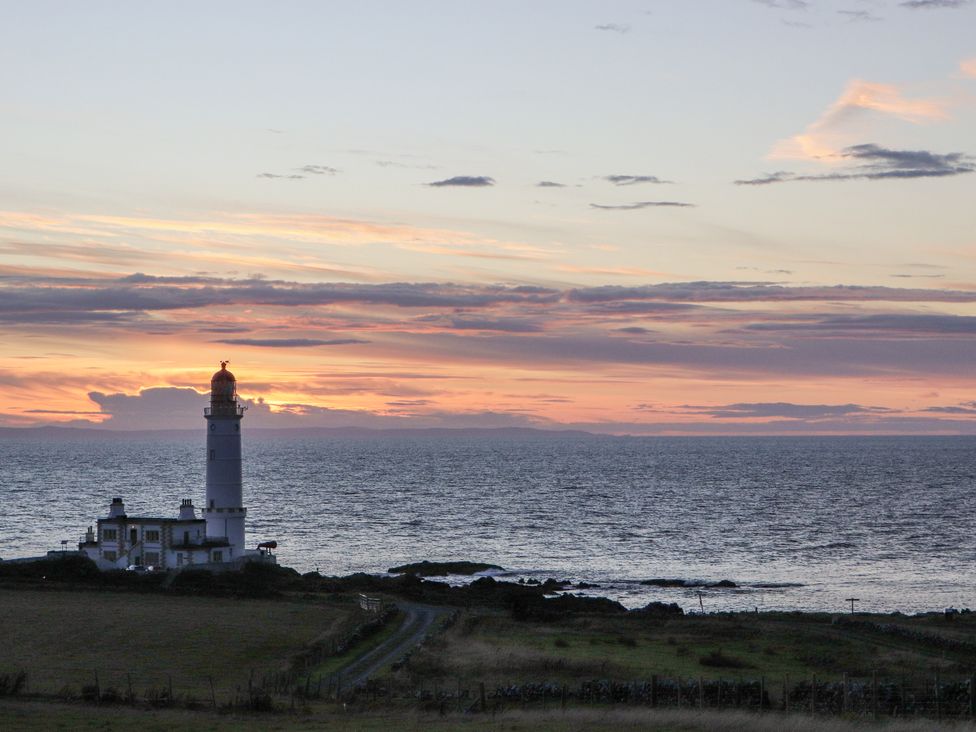 A lighthouse by the ocean at Squirrel Cottage in Kirkcolm