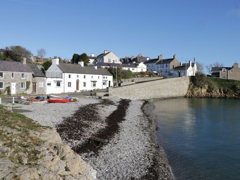A view of houses by the shore with boats and pebbles at Big Azzles in Benllech