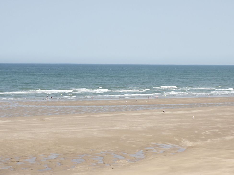 A beach scene with sand and ocean at Big Azzles in Benllech