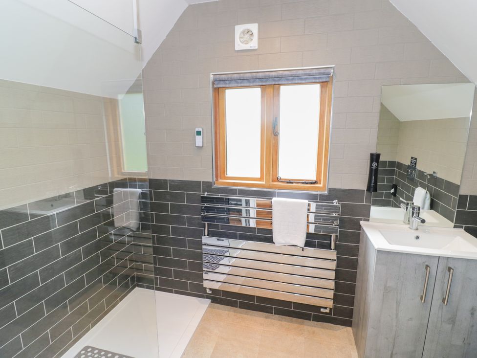 A bathroom with a shower, sink, and mirror at The Coach House in Chacombe