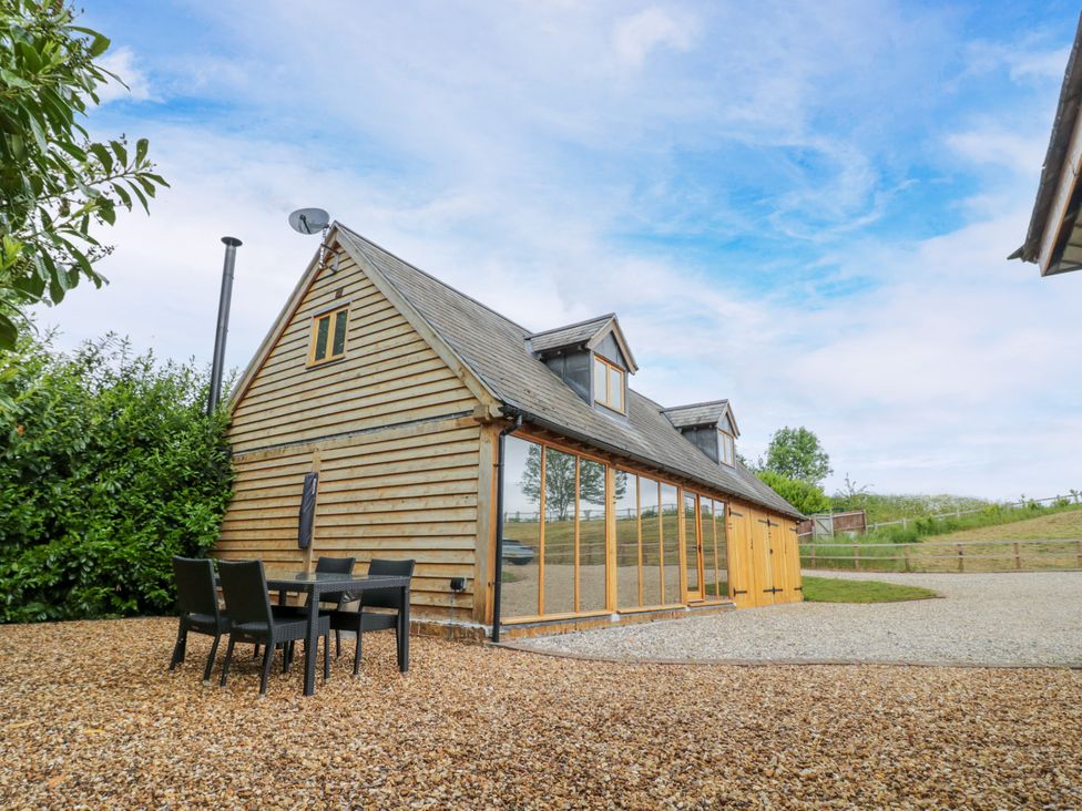 An outdoor area with a table and chairs in front of a wooden house at The Coach House in Chacombe