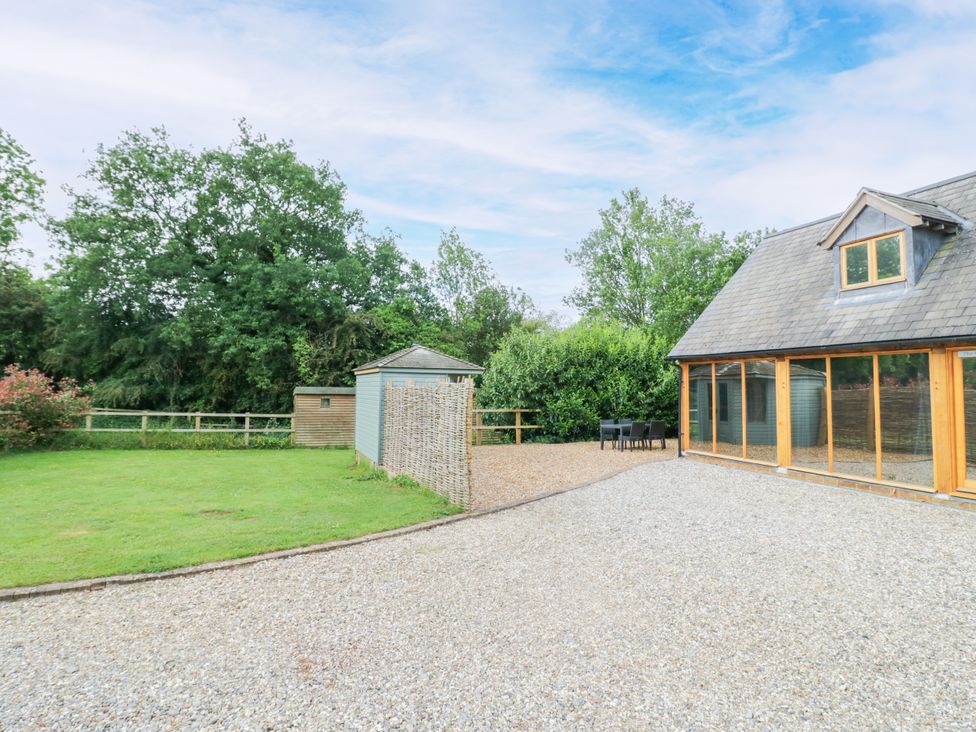 An outdoor area with a house, table, chairs, and shed at The Coach House in Chacombe