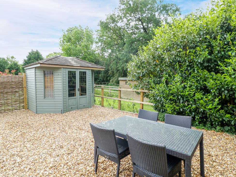 A garden with a table and chairs next to a shed at The Coach House in Chacombe