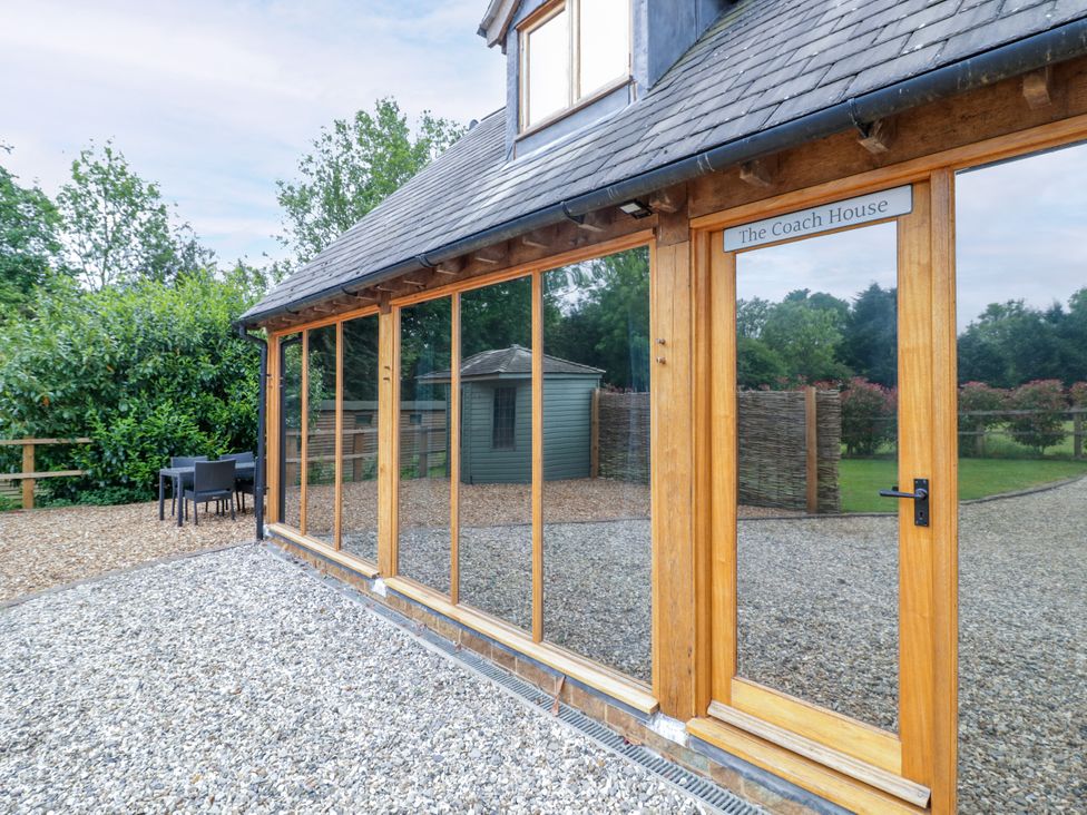 An outdoor area with a building featuring large windows at The Coach House in Chacombe