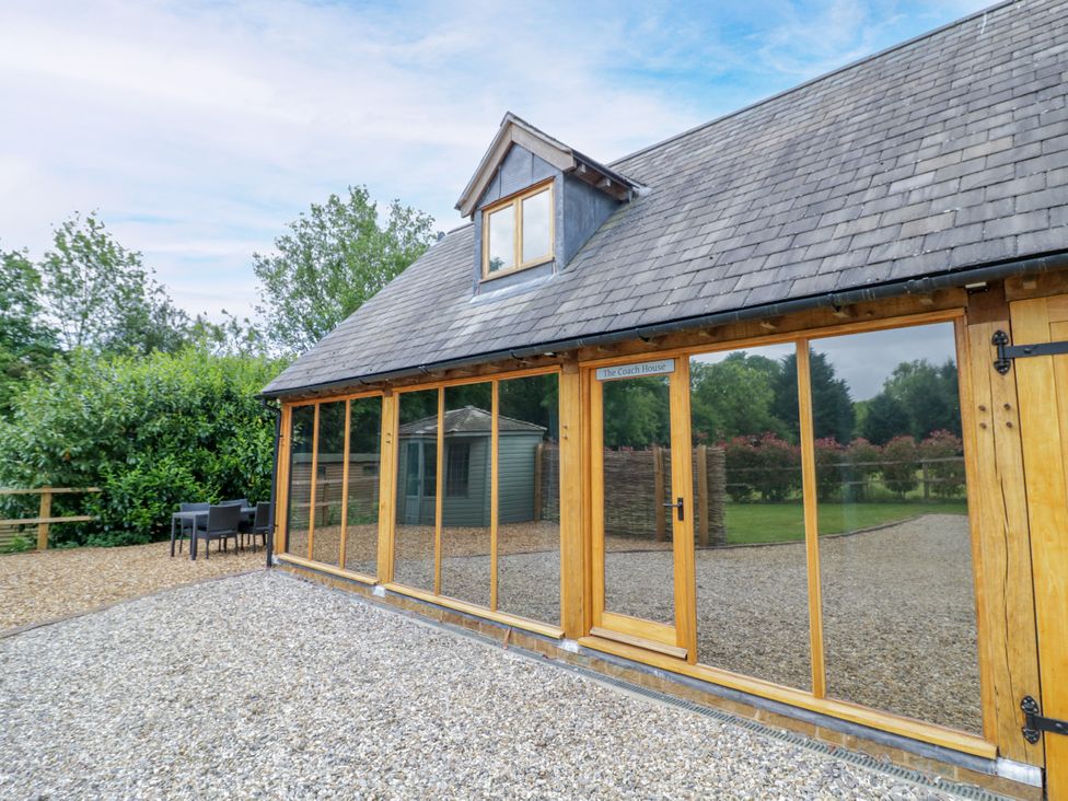 An outdoor view of The Coach House in Chacombe with a gravel area and trees