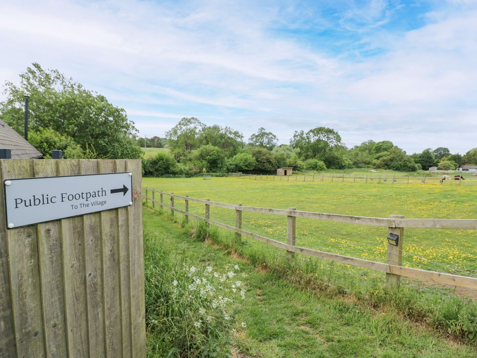 A public footpath sign and fenced area leading to a field at The Coach House in Chacombe