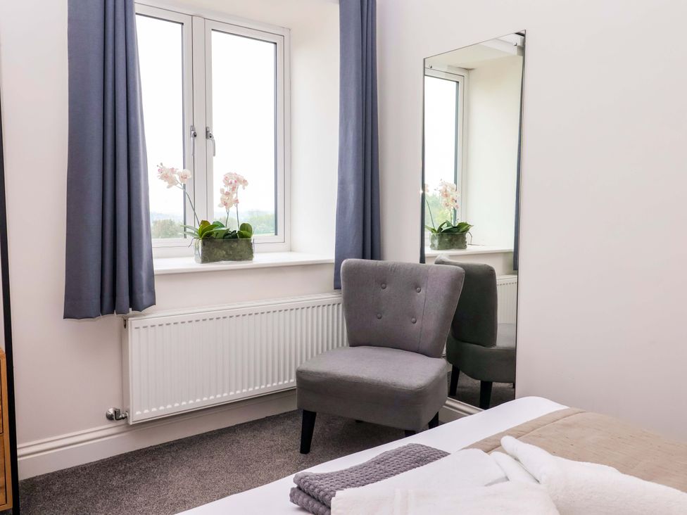 A bedroom with a chair and a window at Ploughman's Rigg in Follifoot near Spofforth