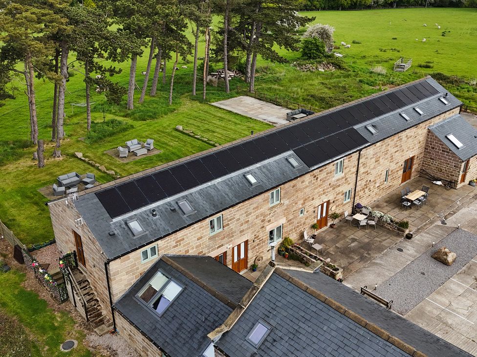 An outdoor view of a stone building with solar panels and patio furniture at Ploughman's Rigg Follifoot near Spofforth
