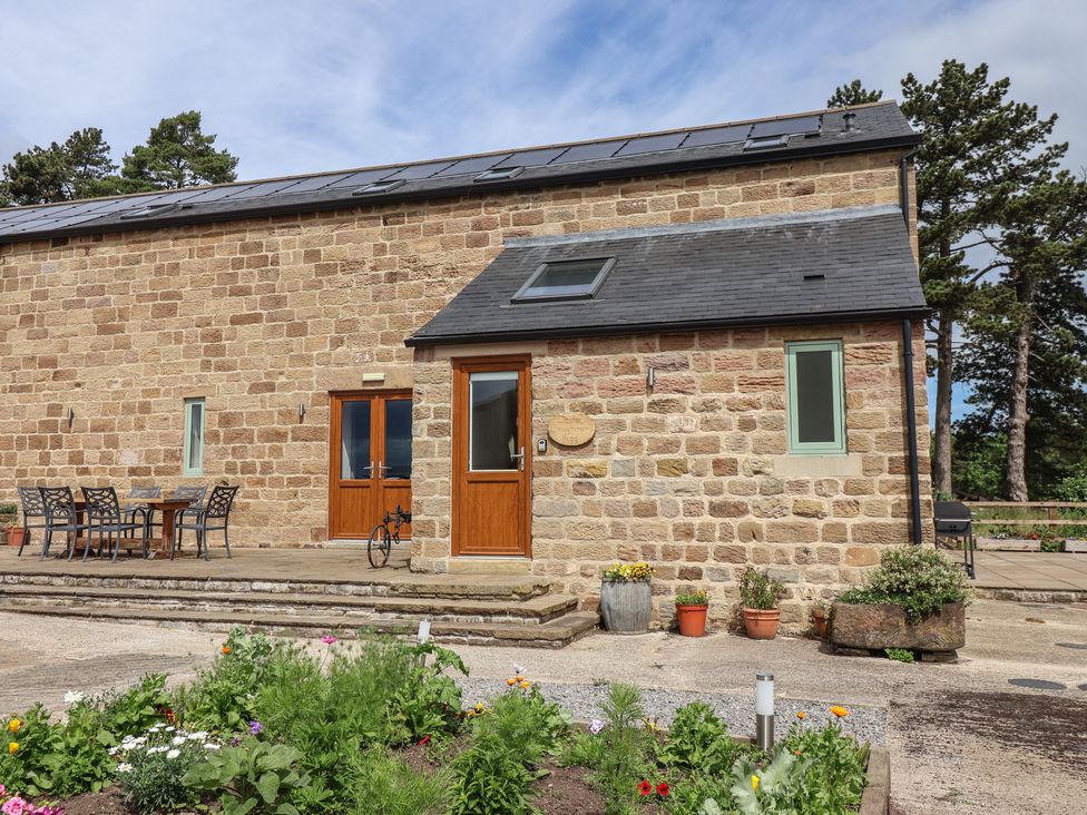 An exterior view of a stone building with a patio and seating area at Ploughman's Rigg Follifoot near Spofforth