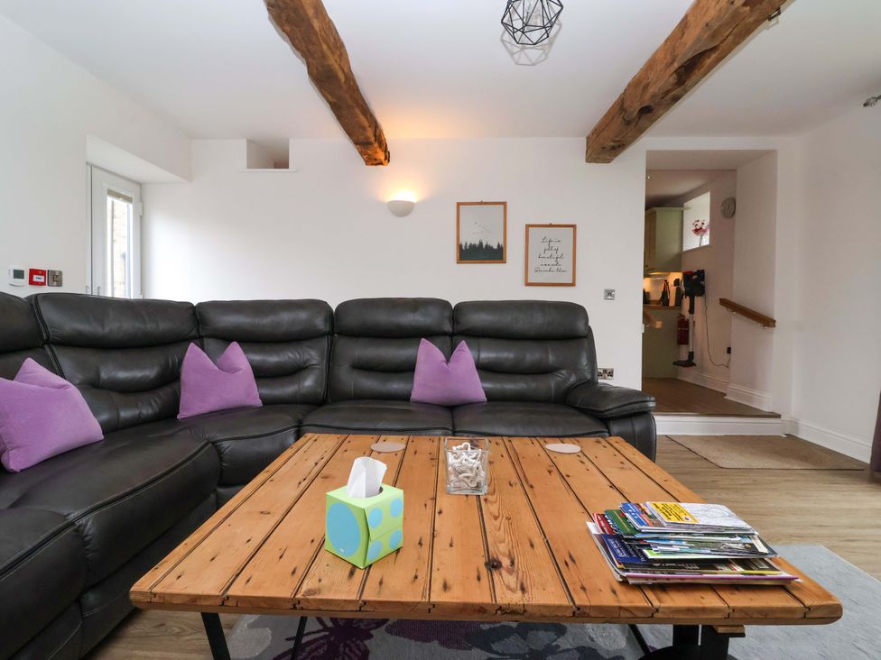 A living room with a sectional sofa and a wooden coffee table at Miller's Wheel in Spofforth