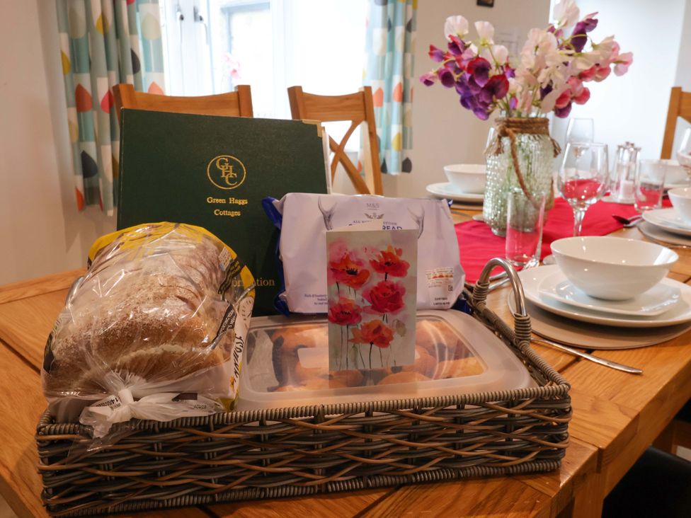 A dining table with bread, a card, and decorative flowers at Miller's Wheel in Spofforth