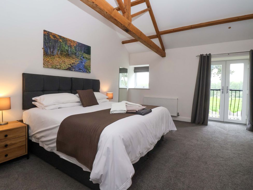 A bedroom with a bed and a view of the garden at Miller's Wheel in Spofforth