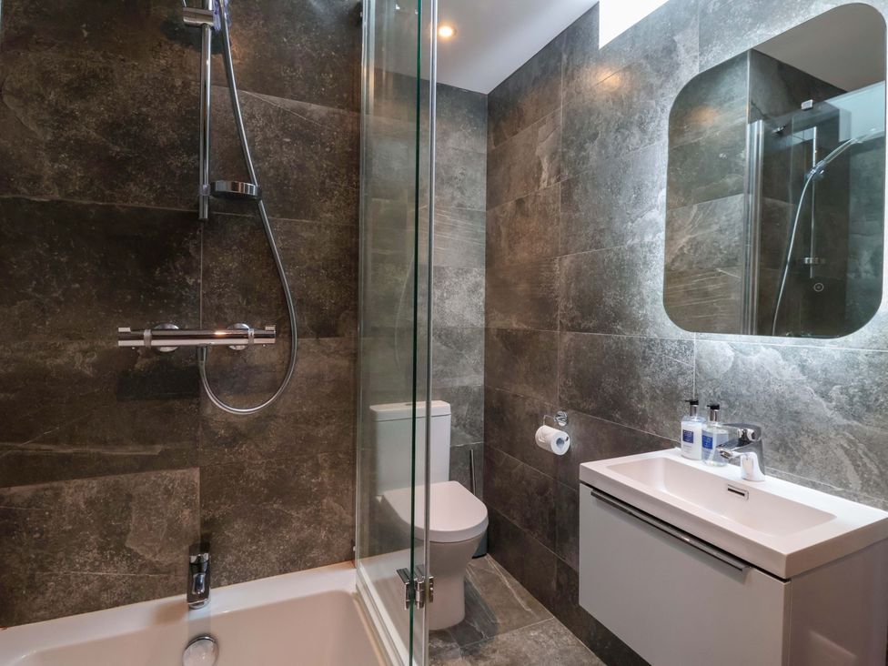 A bathroom with a bathtub, sink, toilet, and shower at Miller's Wheel in Spofforth