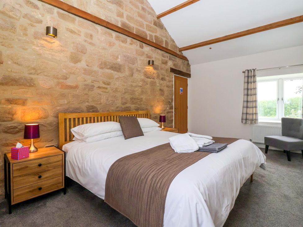 A bedroom with a bed and nightstand at Miller's Wheel in Spofforth
