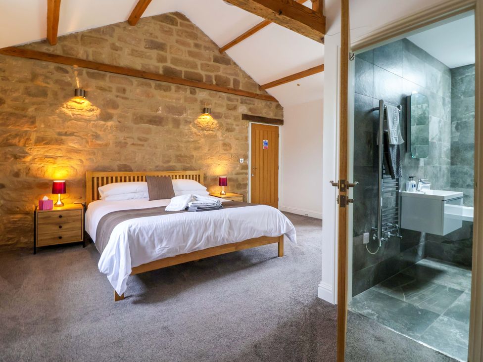 A bedroom with a bed and en-suite bathroom at Miller's Wheel in Spofforth
