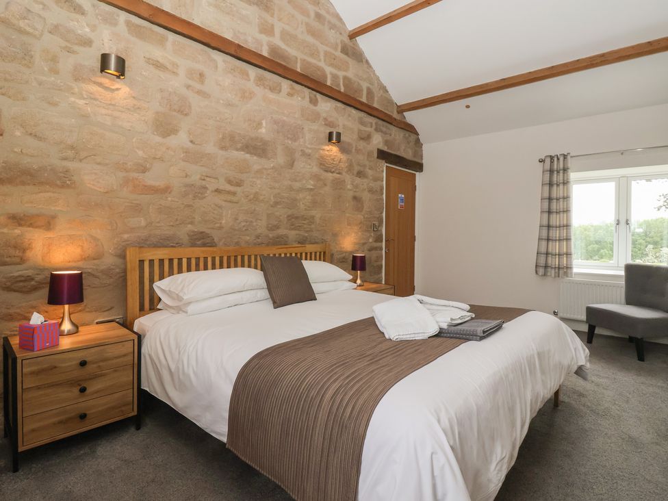 A bedroom with a bed and a chair at Miller's Wheel in Spofforth
