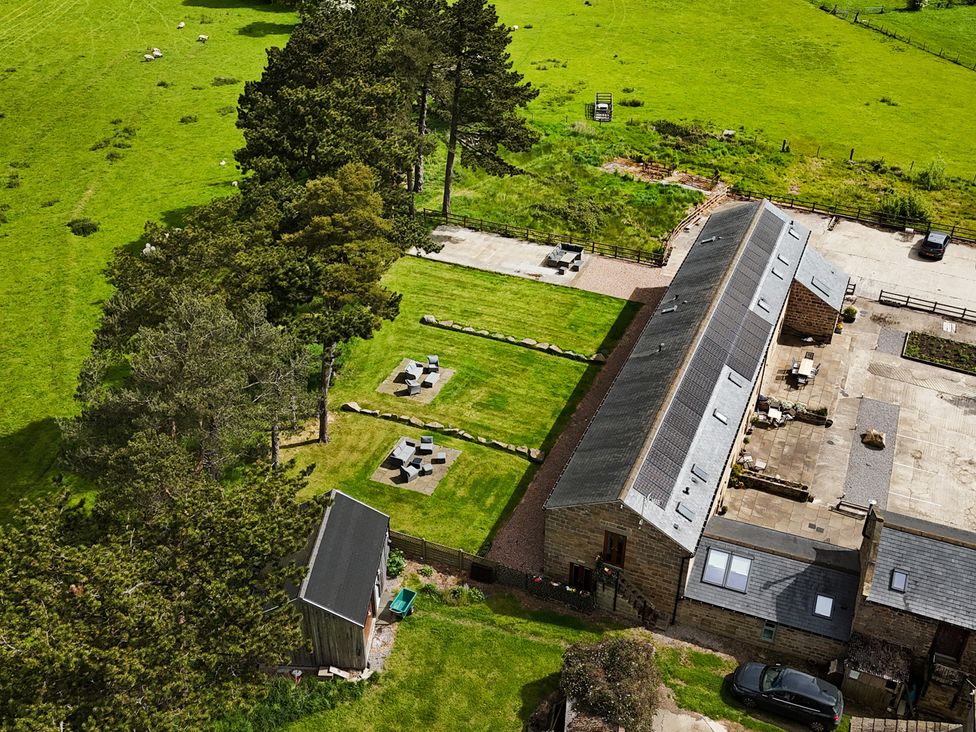 An outdoor area with grass, trees, a building and seating at Shepherd's Crook in Follifoot near Spofforth