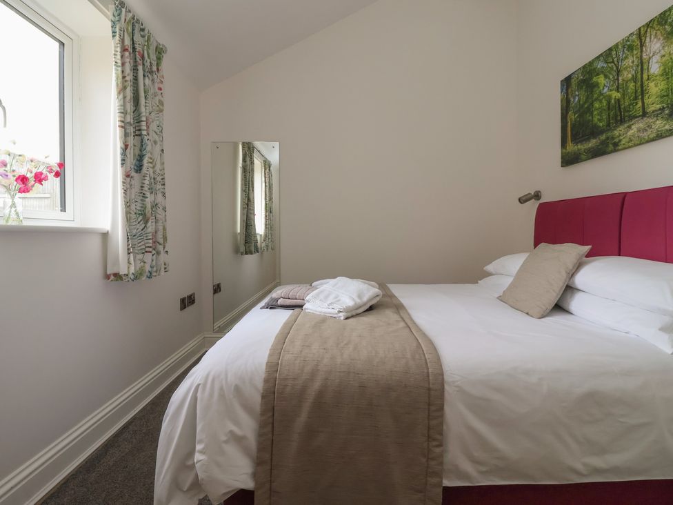 A bedroom with a pink bed and a mirror at Shepherd's Crook in Follifoot near Spofforth