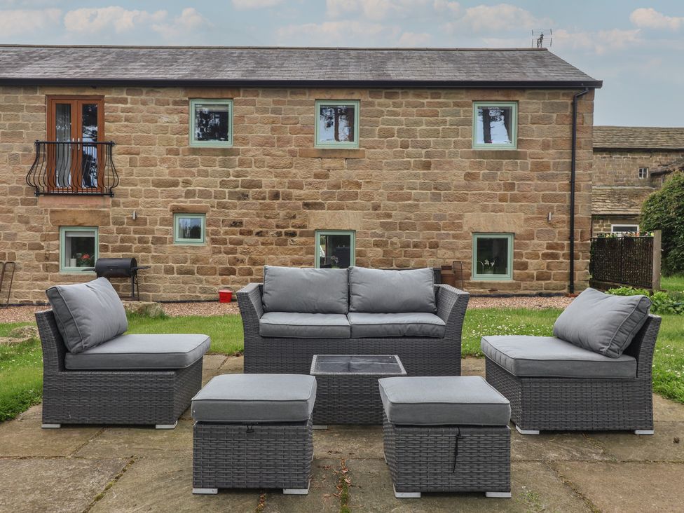 A garden with a seating area featuring a sofa and coffee table at Shepherd's Crook in Follifoot near Spofforth