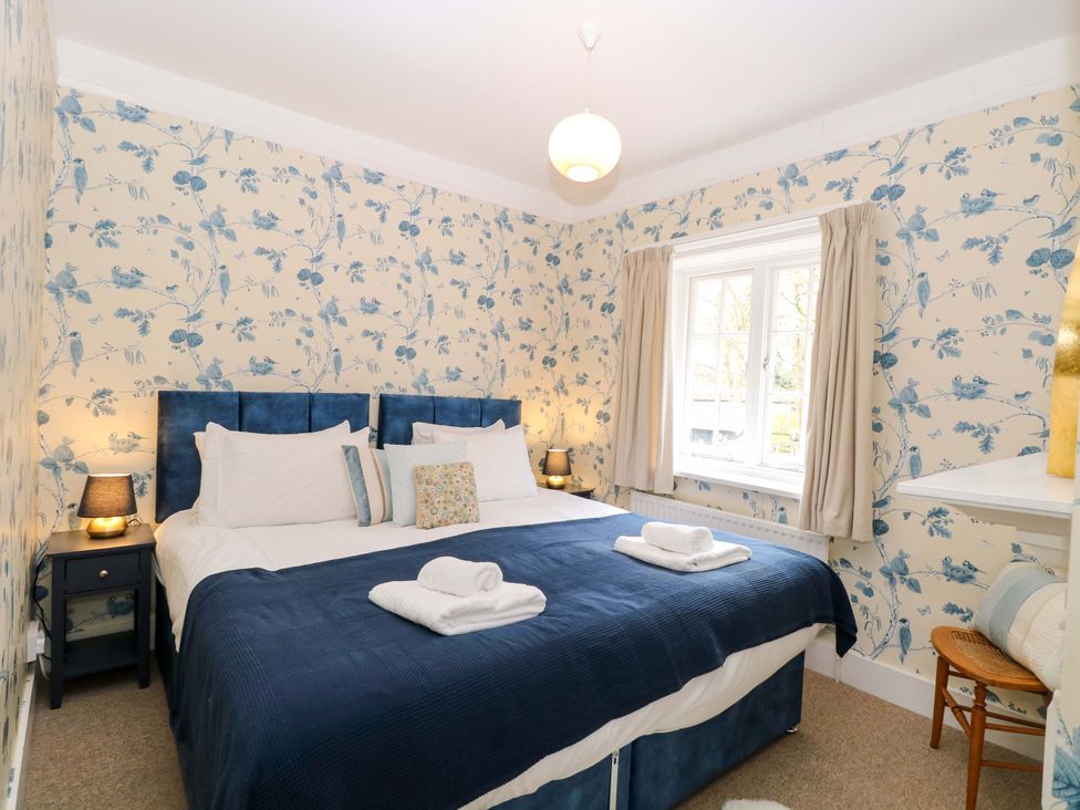 A bedroom with a bed and bedside table at Beckhythe Cottage in Overstrand
