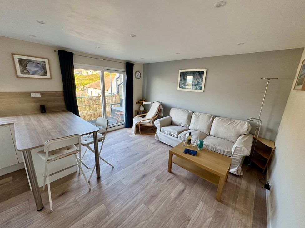 A living room with a sofa and dining space at Gecko Beach in Porthtowan