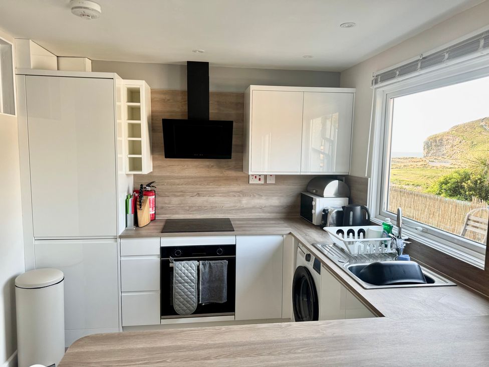 A kitchen with cabinets, oven, and sink at Gecko Beach in Porthtowan