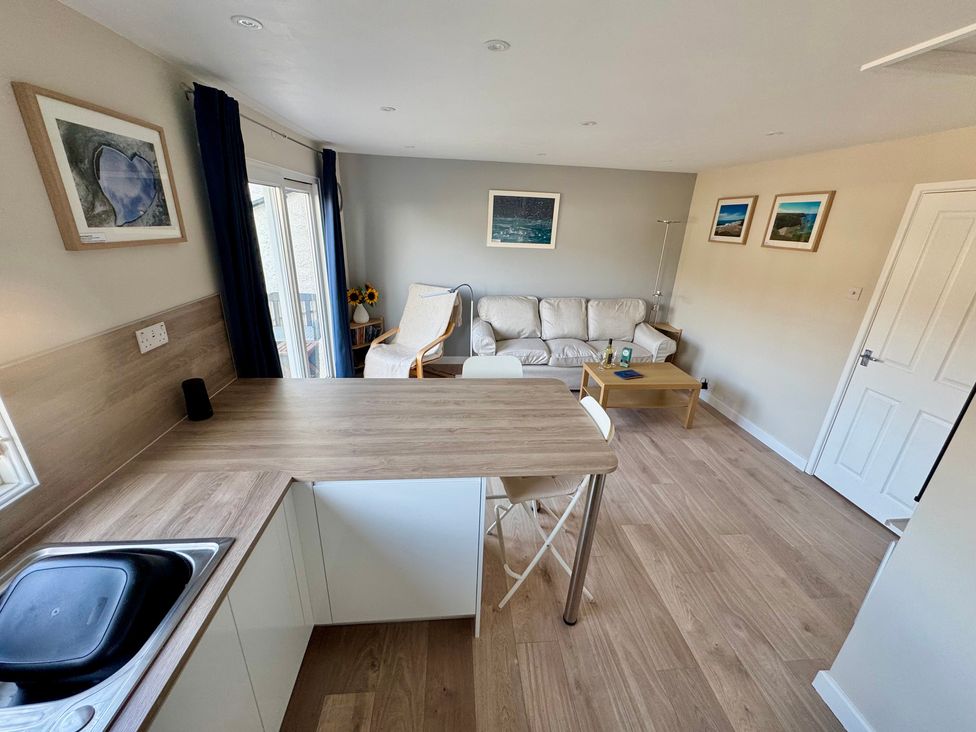 A living room with a sofa and table at Gecko Beach in Porthtowan