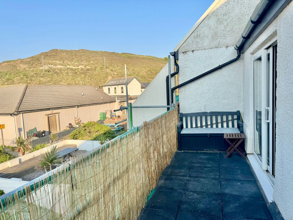 A balcony with a bench and table at Gecko Beach in Porthtowan