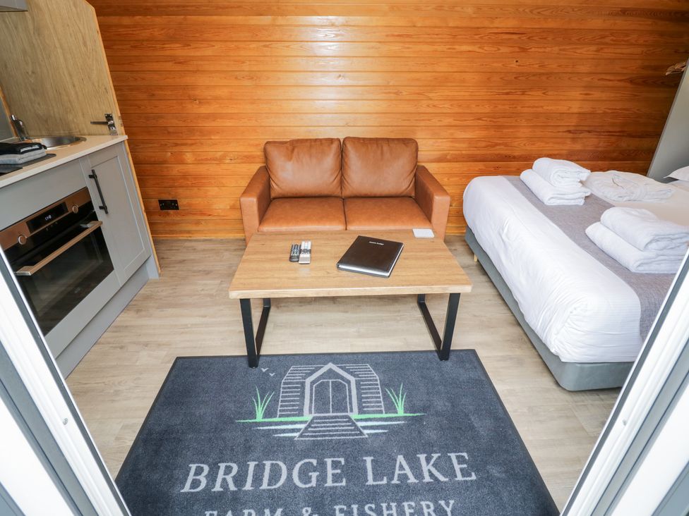 A living room with a sofa and kitchen unit at Acorn Lodge At Bridge Lake Farm & Fishery Chacombe