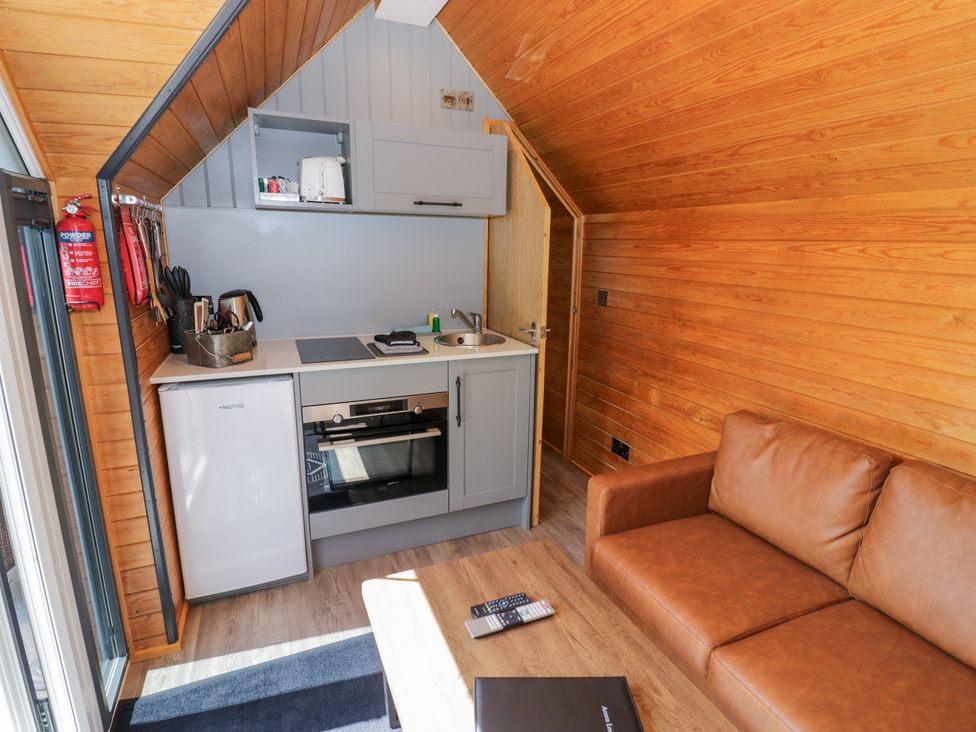 A kitchen with appliances and a sofa at Acorn Lodge At Bridge Lake Farm & Fishery Chacombe