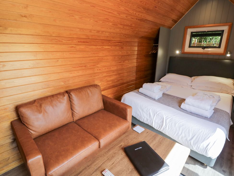 A bedroom with a bed and a sofa at Acorn Lodge At Bridge Lake Farm & Fishery Chacombe