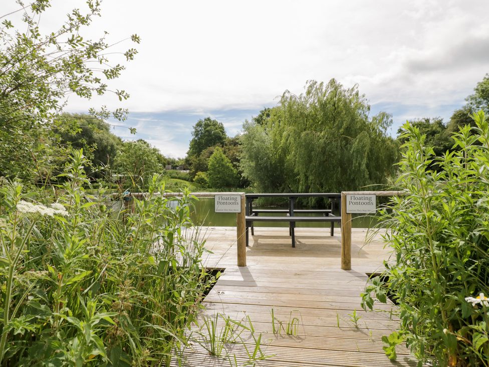 A deck with a bench and signs for floating pontoons at Acorn Lodge At Bridge Lake Farm & Fishery, Chacombe
