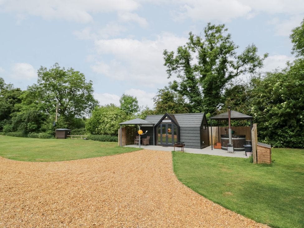 An outdoor view of a cabin with a deck and hot tub at Acorn Lodge At Bridge Lake Farm & Fishery Chacombe