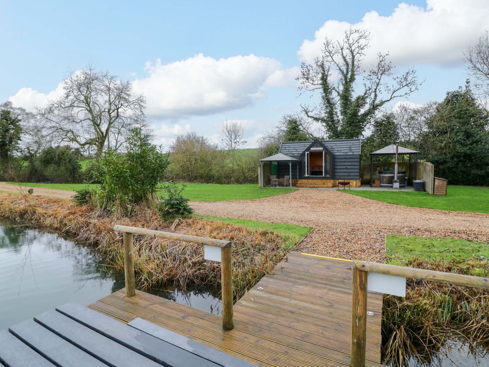 A cabin with a dock and garden area at Acorn Lodge At Bridge Lake Farm & Fishery Chacombe