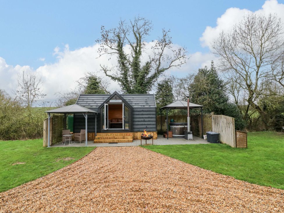 A cabin with outdoor seating and a fire pit at Acorn Lodge At Bridge Lake Farm & Fishery Chacombe