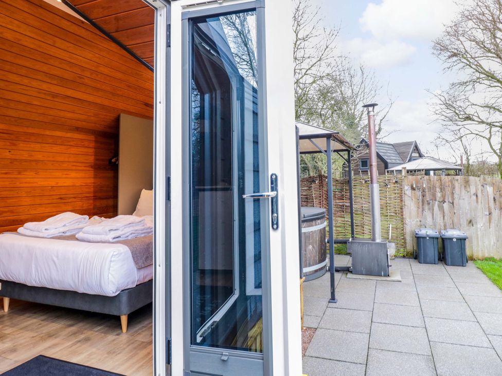 A bedroom with towels on a bed and outdoor area with hot tub at Acorn Lodge At Bridge Lake Farm & Fishery Chacombe