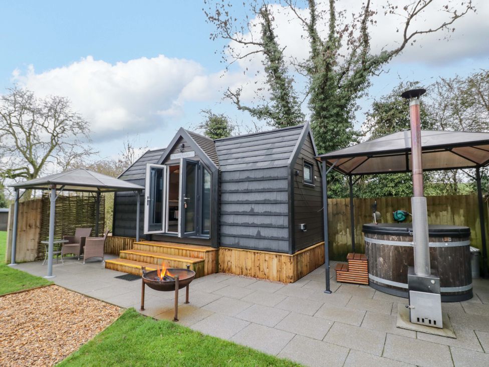 A hot tub and fire pit by a deck at Acorn Lodge At Bridge Lake Farm & Fishery Chacombe