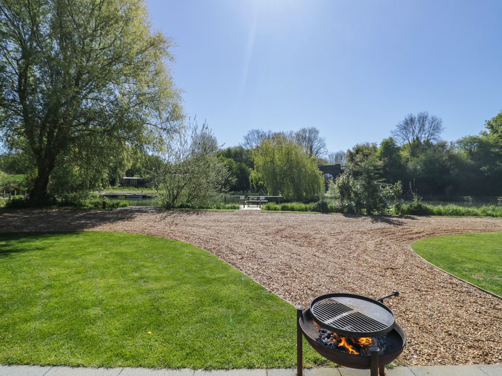 A garden with a barbecue grill and a view of water at Acorn Lodge At Bridge Lake Farm & Fishery Chacombe