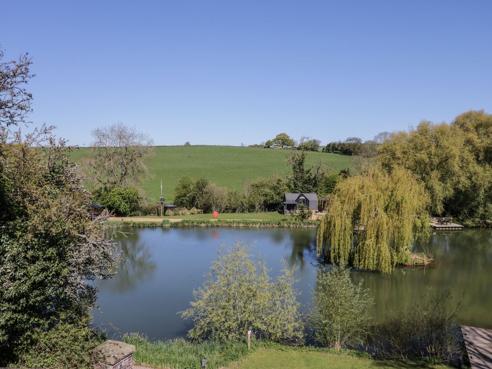A view of a lake surrounded by greenery at Acorn Lodge At Bridge Lake Farm & Fishery Chacombe