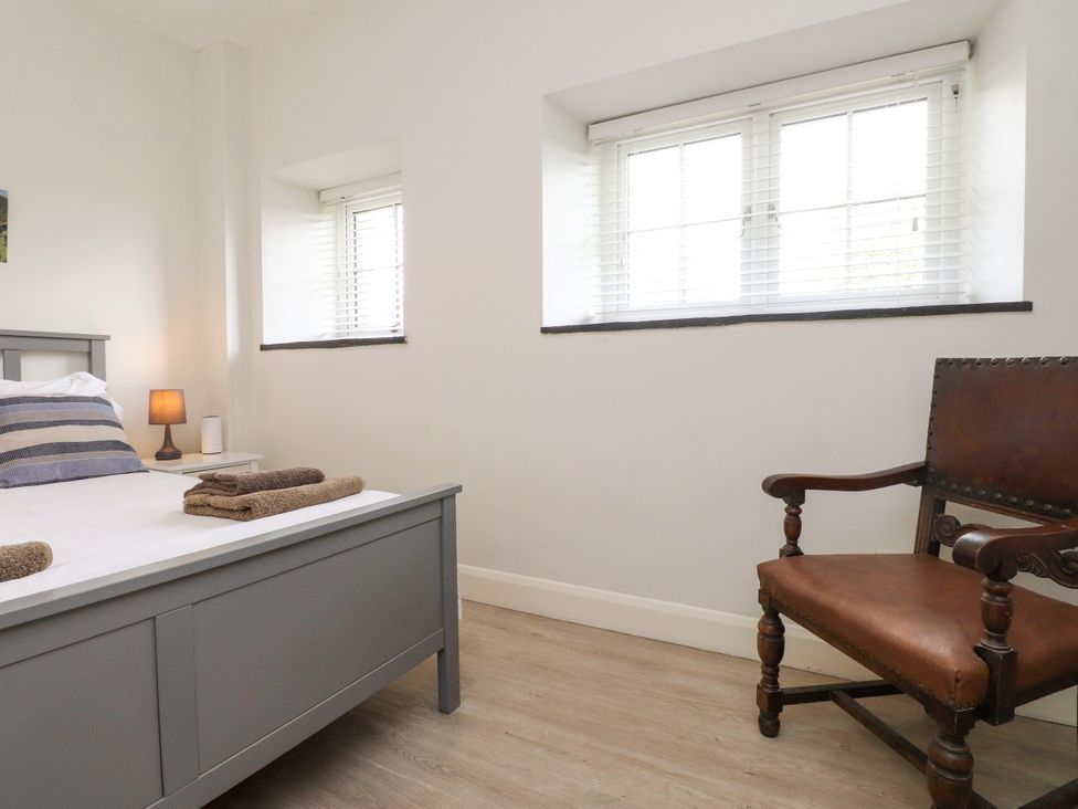 A bedroom with a bed, lamp, and chair at Pen Y Cefn in Pen Y Cefn