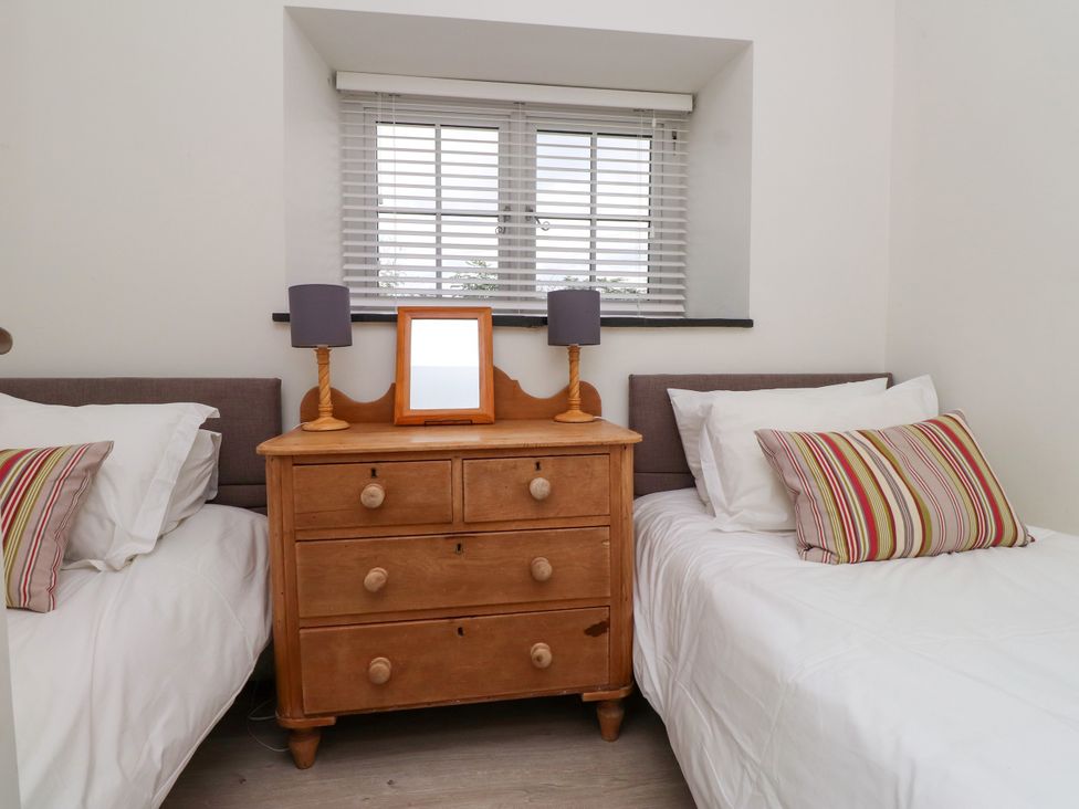 A bedroom with two beds and a wooden dresser at Pen Y Cefn