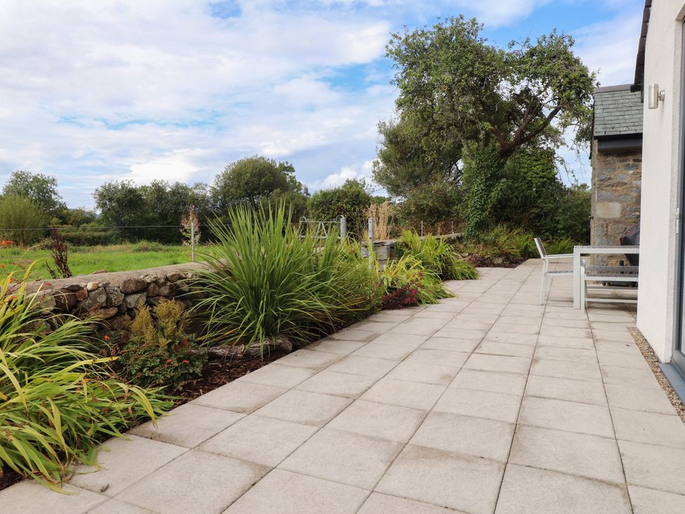 An outdoor patio with stone wall and plants at Pen Y Cefn in Pen Y Cefn