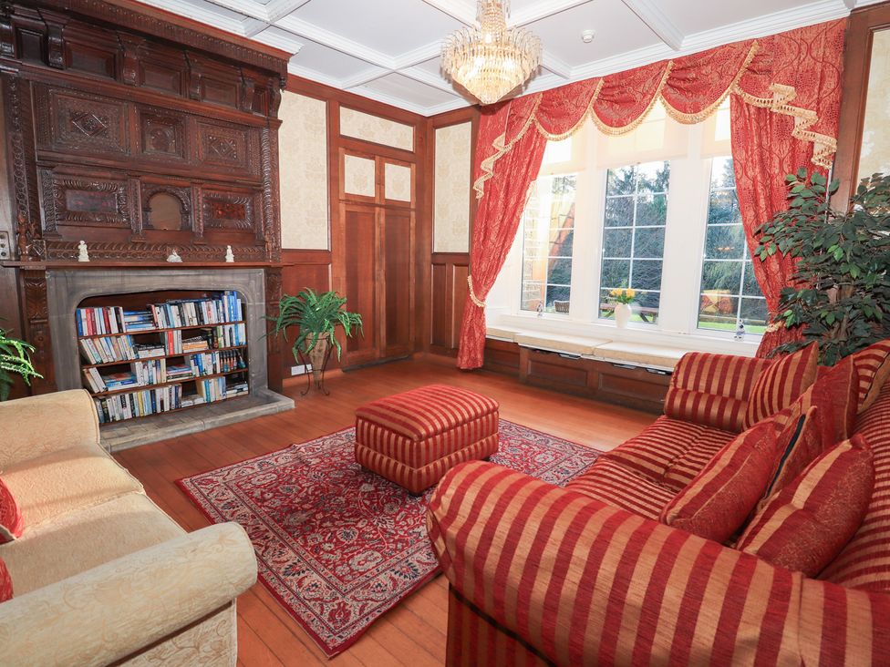 A living room with a sofa and a bookshelf at Auchentroig House Buchlyvie