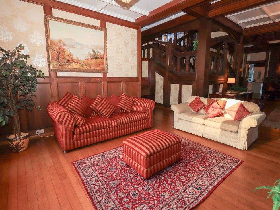 A living room with a red sofa and artwork at Auchentroig House in Buchlyvie