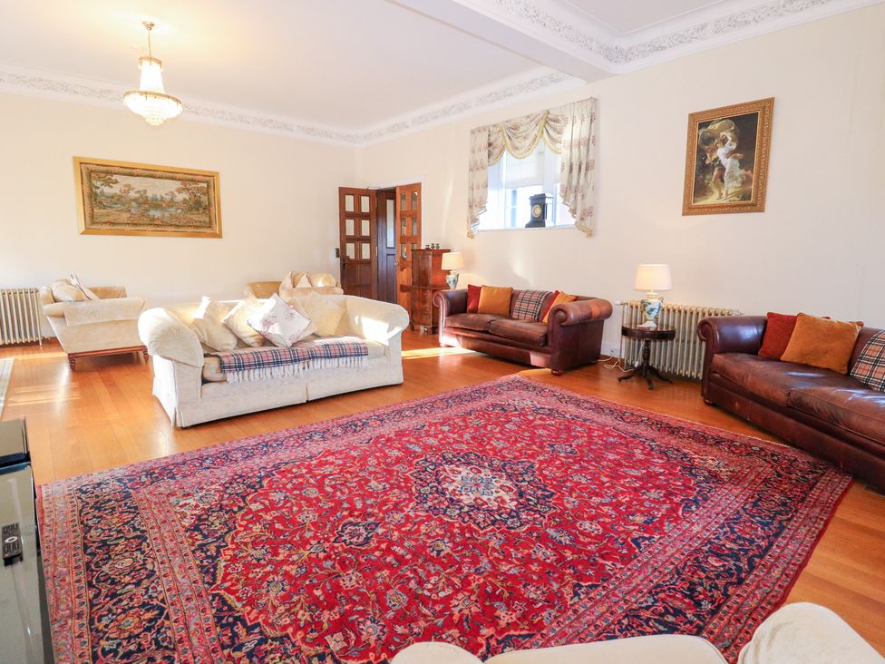 A living room with sofas, a coffee table, and a rug at Auchentroig House in Buchlyvie