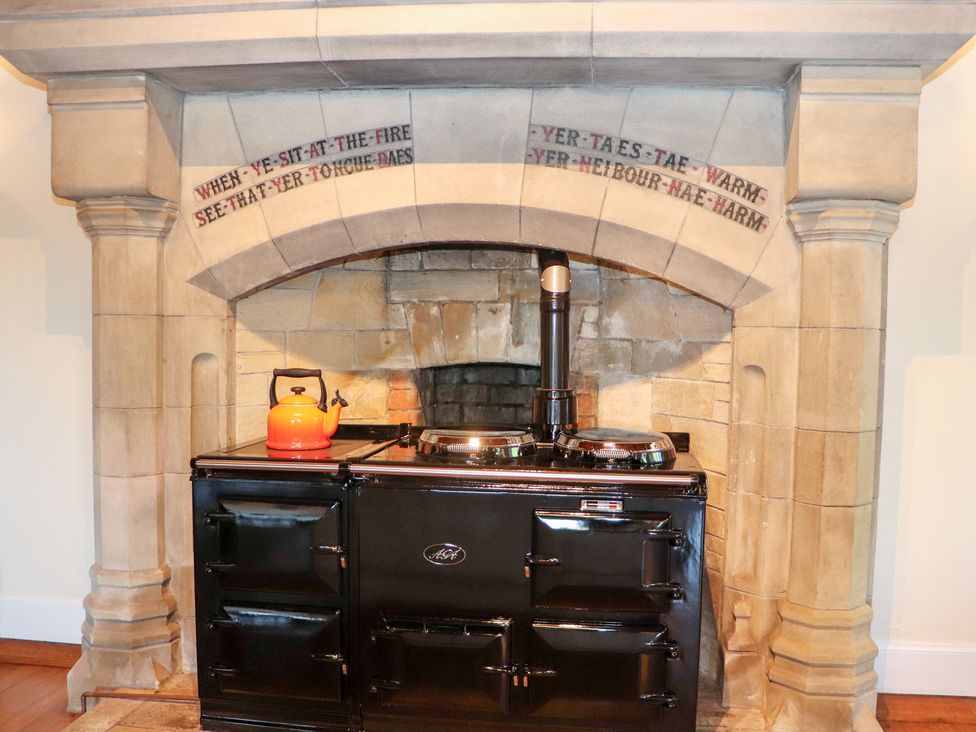 A kitchen with a black stove and orange kettle at Auchentroig House in Buchlyvie