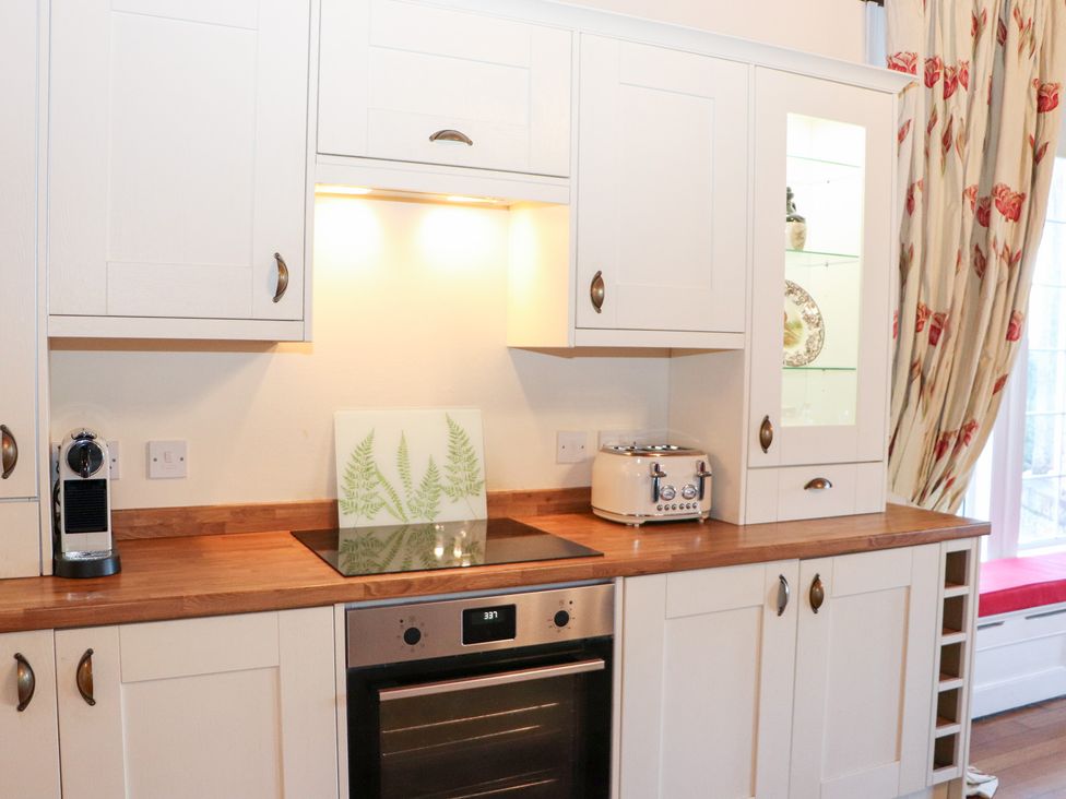 A kitchen with white cabinets and wooden countertop at Auchentroig House in Buchlyvie
