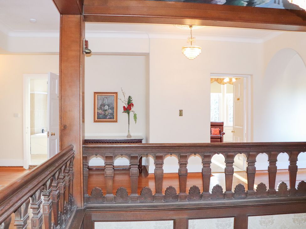 A hallway with a balustrade and paintings at Auchentroig House Buchlyvie