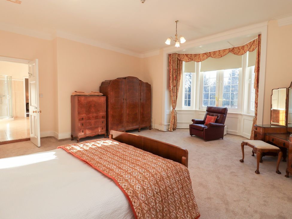 A bedroom with a bed and wardrobe at Auchentroig House in Buchlyvie